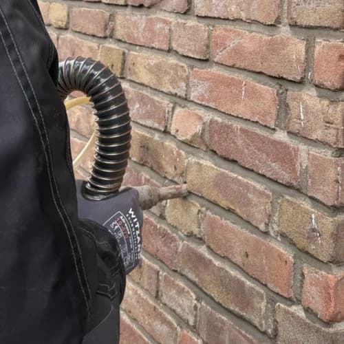 Monteur die isolatiemateriaal in de spouwmuur van een woning blaast